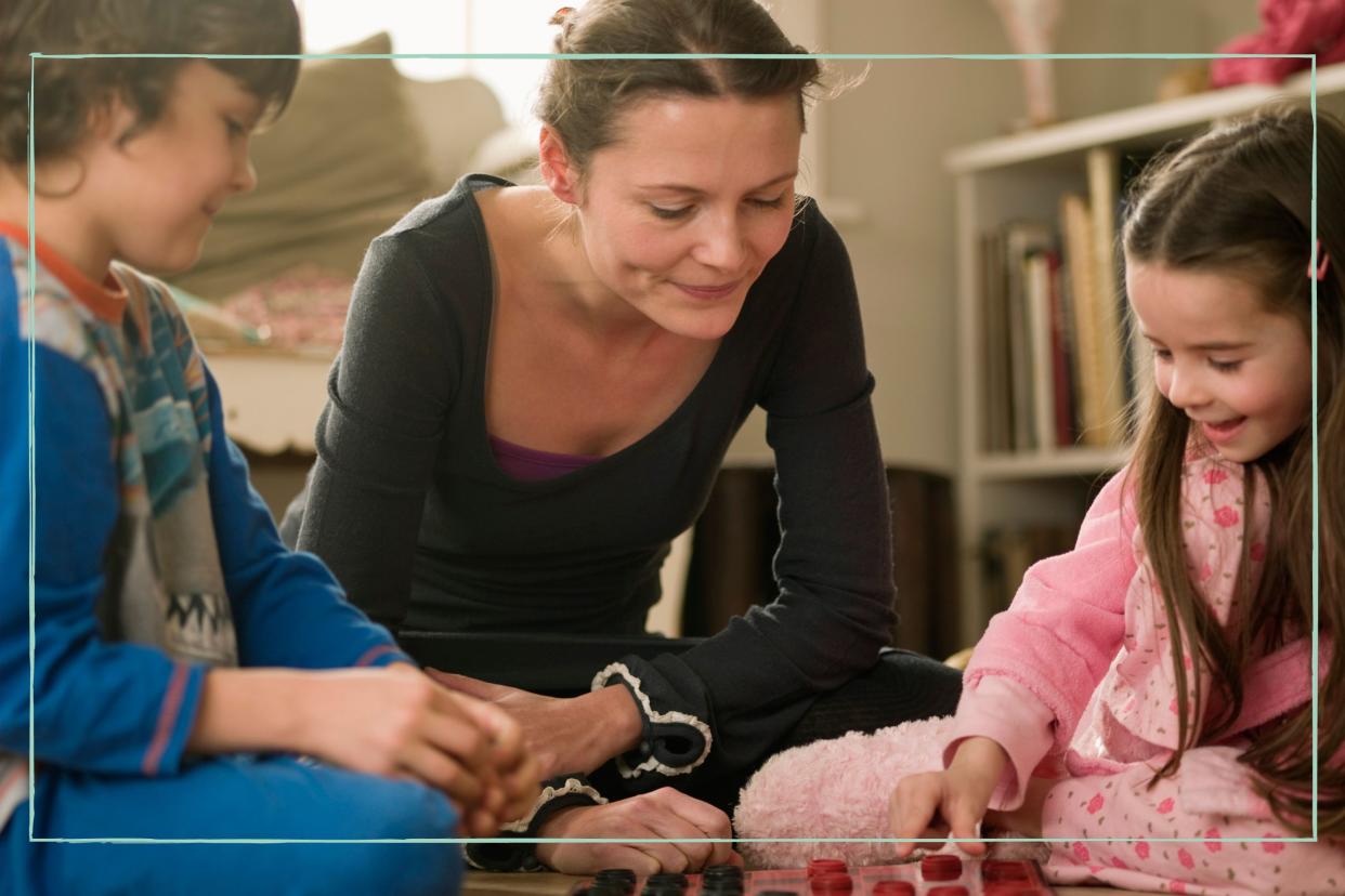  Mum playing board game on the floor with her two children. 