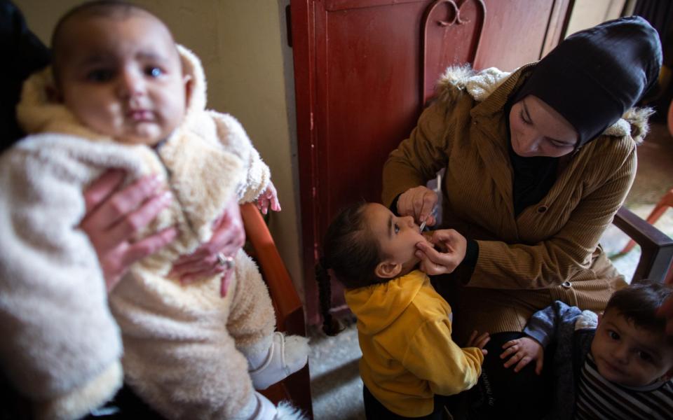 A girl receives receives an oral cholera vaccine from Lebanese Red Cross staff at her home in Bebnine - ELISA ODDONE