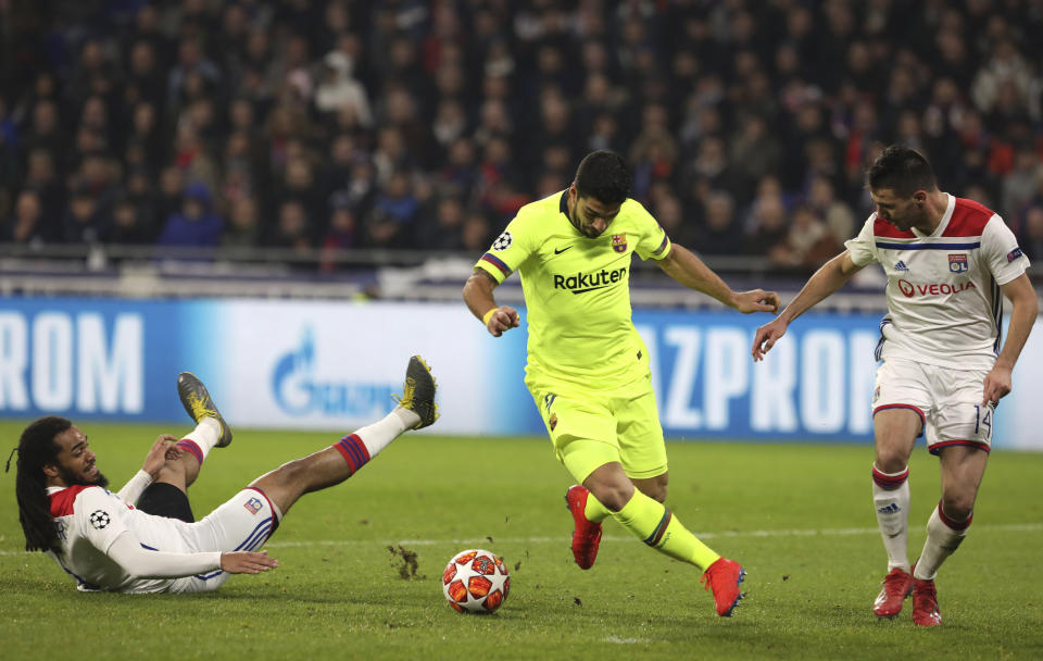 Lyon defender Jason Denayer, left, and Lyon defender Leo Dubois, right, challenge Barcelona forward Luis Suarez, center, during the Champions League round of 16 first leg soccer match between Lyon and FC Barcelona in Decines, near Lyon, central France, Tuesday, Feb. 19, 2019. (AP Photo/Laurent Cipriani)