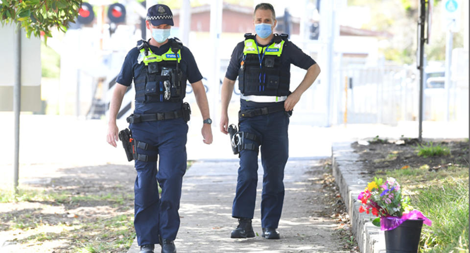 Victoria Police walk past flowers at the scene where a man was stabbed near Seaford Train station in Melbourne, Thursday. Source: AAP  