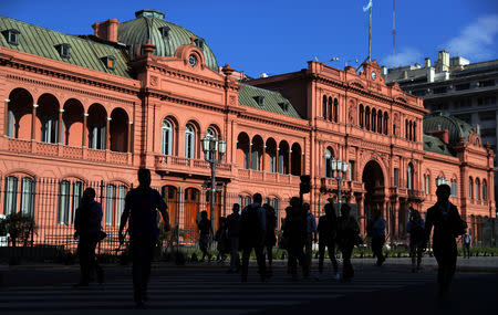 People are silhouetted as they cross the street outside the Casa Rosada Presidential Palace in Buenos Aires, Argentina October 18, 2018. Picture taken October 18, 2018. REUTERS/Marcos Brindicci