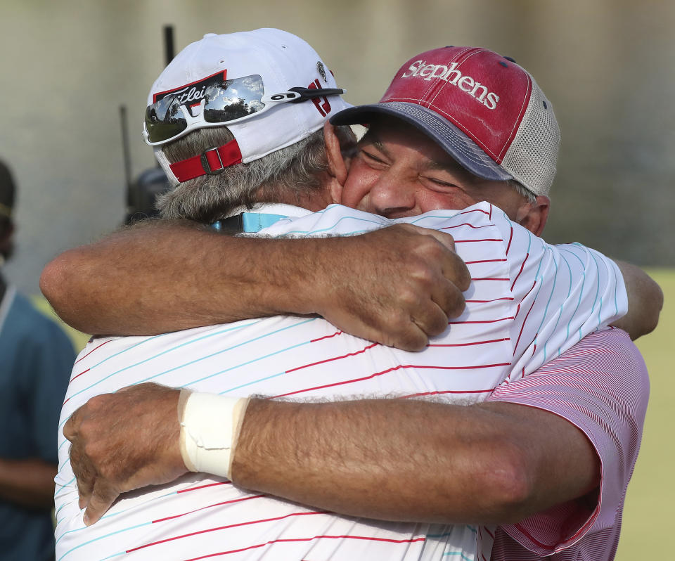 Dicky Pride, right, gets a hug from Woody Austin after sinking his par putt on the 18th hole to win the PGA Tour Champions’ Mitsubishi Electric Classic golf tournament at TPC Sugarloaf on Sunday, May 16, 2021, in Duluth, Ga. (Curtis Compton/Atlanta Journal-Constitution via AP)