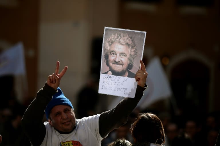 A supporter of anti-establishment party Five Star movement holds a portrait of its leader Beppe Grillo in front of the Montecitorio palace, the Italian Chamber of Deputies, in Rome, on February 15, 2014