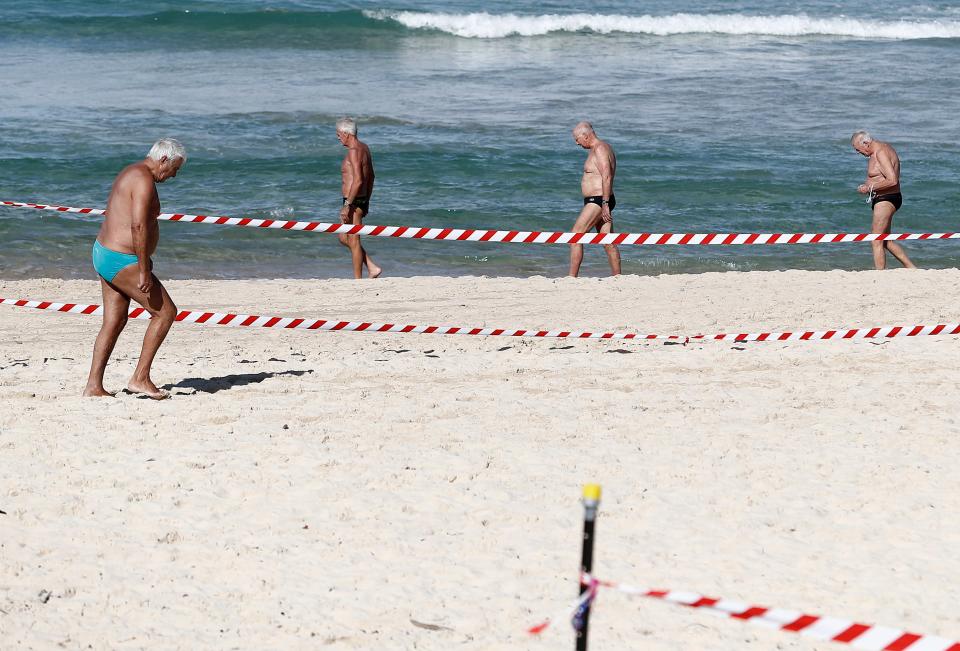 A group of men walk on Bondi Beach on May 1, 2020, in Sydney, Australia.