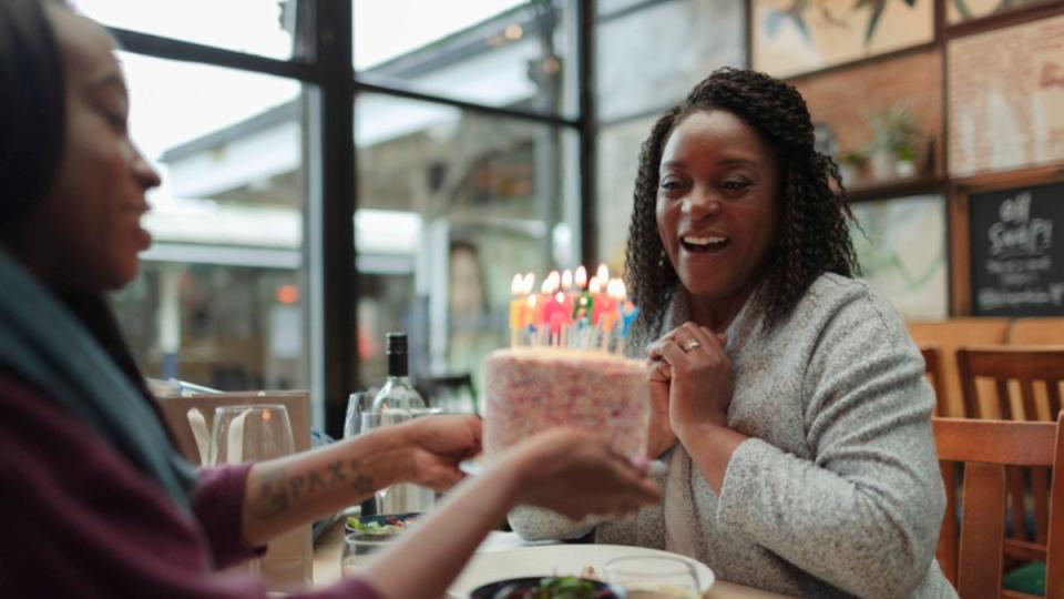 A mature woman celebrating her birthday with a birthday cake, thanks to the benefits of an increased lifespan from astaxanthin