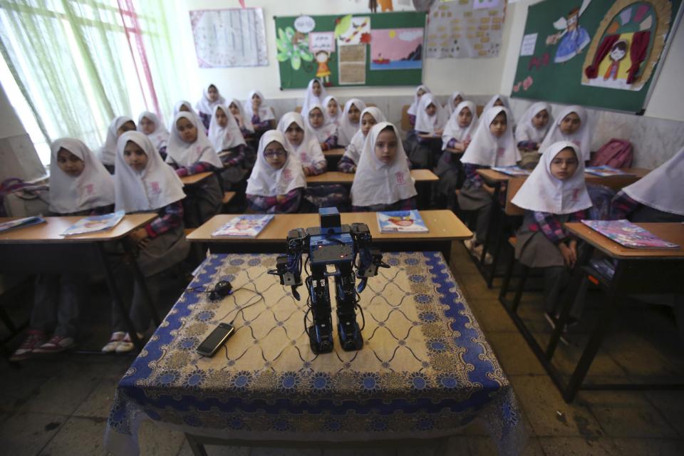 In this picture taken on Monday, Feb. 24, 2014, Veldan, a humanoid praying robot which is built by Iranian schoolteacher Akbar Rezaie, performs morning prayer in front of Alborz elementary school girls in the city of Varamin some 21 miles (35 kilometers) south of the capital Tehran, Iran. Rezaei who has built a robot to show to children how to execute daily prayers, has innovated an amusing way of encouraging young children to say their daily prayers by using the science of robotics. Out of personal interest and unrelated to his field of study, Akbar Rezaei attended private robotics classes and acquired the skill of assembling and developing customized humanoid robots. He built the robot at home with basic tools and gave it the designation “Veldan”, a term mentioned in Quran meaning: “Youth of Heaven”. By applying some mechanical modifications such as adding up two extra engines Akbar Rezaei managed to let the robot perform praying movements, such as prostration, more easily.(AP Photo/Vahid Salemi)