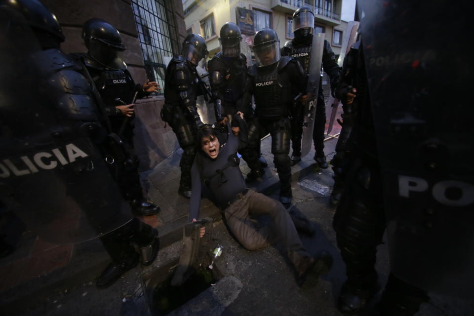 In this April 16, 2019 photo, a man is detained by police blocking protesters from advancing closer to the presidential palace in Quito, Ecuador. Protesters were demonstrating against the policies of President Lenin Moreno's government, including the recent firing of state workers, the taking of an IMF loan and the removal of Julian Assange's asylum status. (AP Photo/Dolores Ochoa)