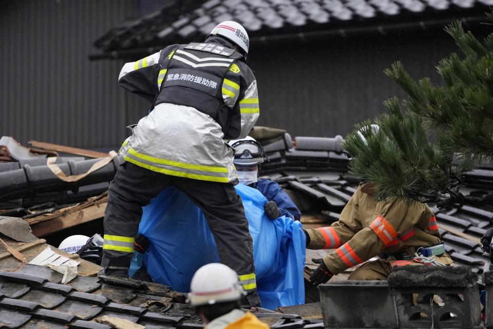 Firefighters and rescue workers pull a body , in blue sheet, found from a collapsed house caused by powerful earthquake in Suzu, Ishikawa Prefecture Wednesday, Jan. 3, 2024. (AP Photo/Hiro Komae)