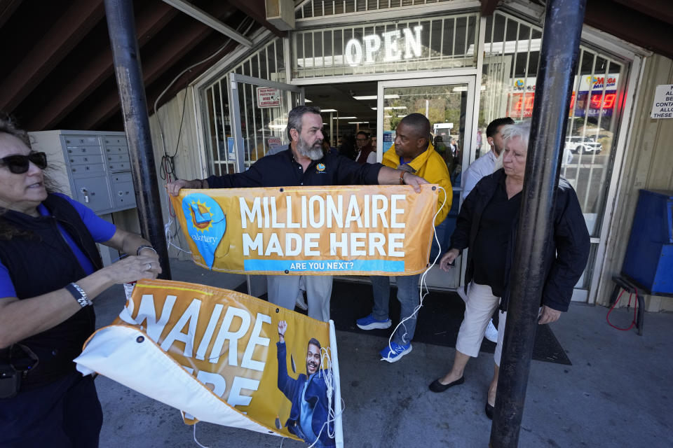 Lottery officials put up banners outside the entrance at the Midway Market & Liquor store, Thursday, Oct. 12, 2023, in Frazier Park, Calif., where a $1.765 billion winning Powerball ticket was sold. (AP Photo/Marcio Jose Sanchez)