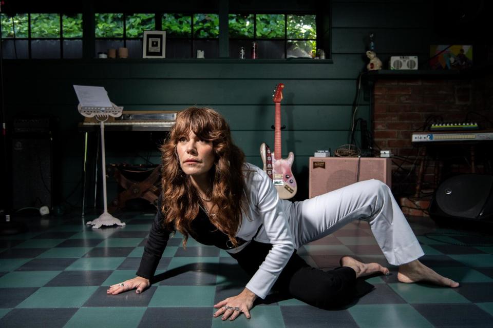 In what looks like a black and white jumpsuit, a barefoot Jenny Lewis strikes a pose on the floor of her L.A. home.