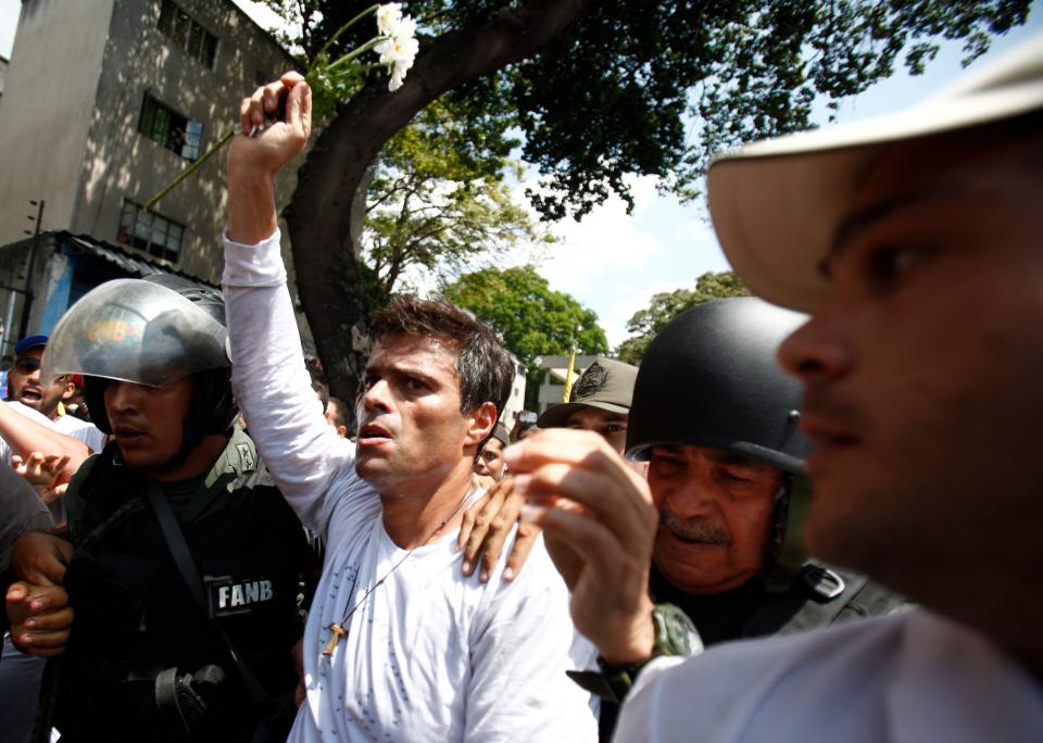 Opposition leader Leopoldo Lopez is flanked by Bolivarian National Guards after Lopez surrendered, in Caracas, Venezuela, Tuesday, Feb 18, 2014. Lopez re-emerged from days of hiding to address an anti-government demonstration and then he turned himself in to authorities Tuesday. Speaking to some 5,000 supporters with a megaphone, Lopez said that he doesn't fear going to jail to defend his beliefs and constitutional right to peacefully protest against President Nicolas Maduro. (AP Photo/Alejandro Cegarra)