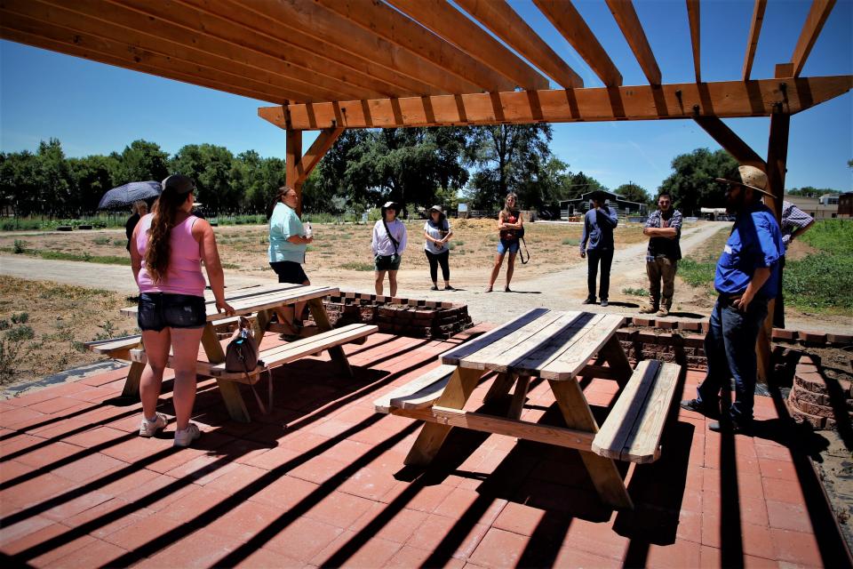 Participants in the Northwest New Mexico Local Food Summit seek shade under a pergola during a visit to the Growing Forward Farm in Aztec on Friday, July 21.