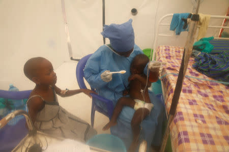 Ebola survivor Jeanine Masika Mbuka holds Furana Katungu, a two-year-old confirmed ebola patient, inside the Biosecure Emergency Care Unit (CUBE) at the ALIMA (The Alliance for International Medical Action) Ebola treatment centre in Beni, Democratic Republic of Congo, March 31, 2019. Picture taken March 31, 2019. Picture taken through a plastic divider. REUTERS/Baz Ratner