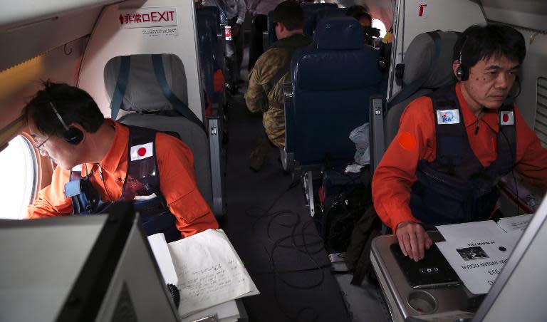 Communications specialists Hidetaka Sato (L) and Fujio Koma (R), on a Japan Coast Guard Gulfstream aircraft, man the comms stations while searching for missing Malaysia Airlines flight MH370 over the southern Indian Ocean on April 1, 2014