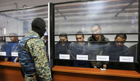 Islamic State supporters, who attacked a National Guard facility in June, sit inside a glass-walled cage during a verdict hearing at a court in Aktobe, Kazakhstan, November 28, 2016. REUTERS/Stringer