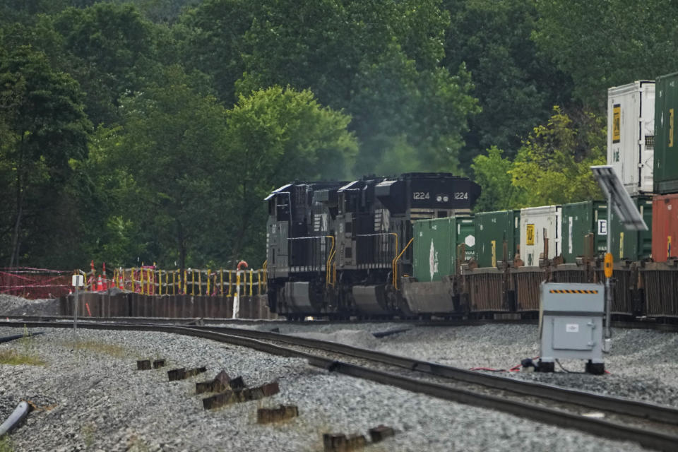 A Norfolk Southern freight train travels through the area where clean-up continues after a train carrying hazardous materials derailed more than a year ago, Tuesday, June 25, 2024, in East Palestine, Ohio. (AP Photo/Sue Ogrocki)