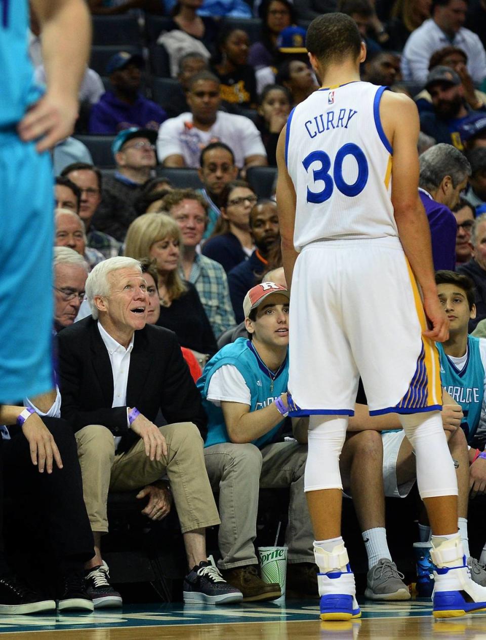 Golden State Warriors guard Steph Curry (right) talks with his former Davidson College coach Bob McKillop (seated) during a 2017 game in Charlotte.
