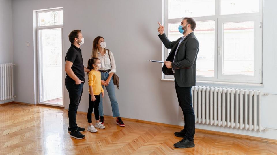 Confident male real estate agent gestures toward a beautiful view out the window of a new home.