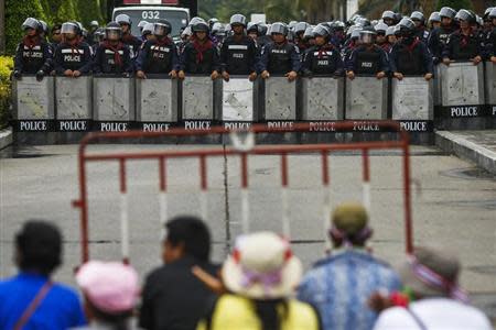 Thai riot police stand guard as anti-government protesters (bottom) rally inside a compound of the Thai Royal Police Club in Bangkok February 21, 2014. REUTERS/Athit Perawongmetha