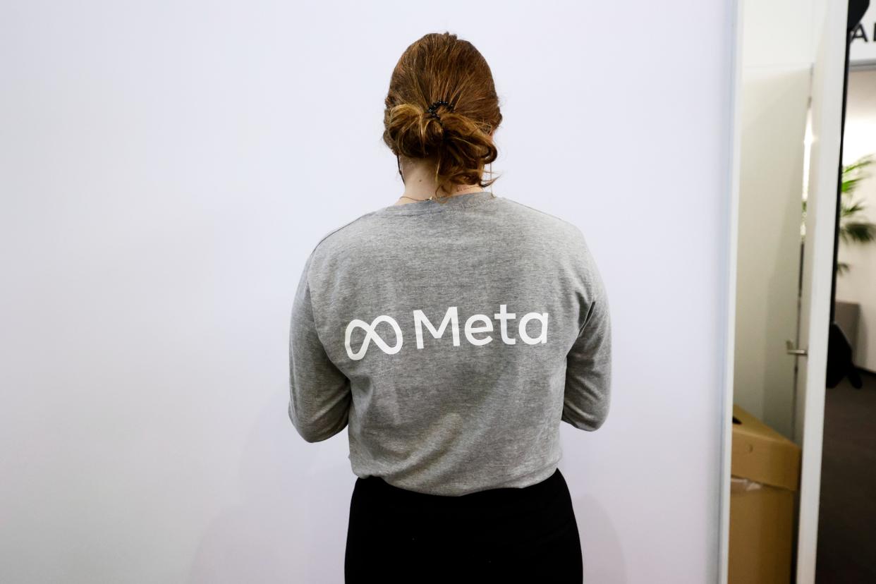 A woman wearing a grey t-shirt with Meta's logo.