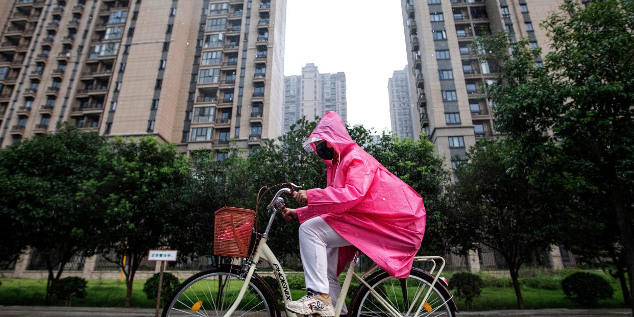 A resident cycles through the Evergrande changqing community in the rain on