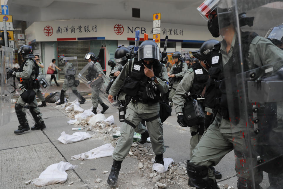 Riot police cross barricade made by protesters during a protest in Hong Kong, Saturday, Oct. 12, 2019. Protesters marching peacefully hit the rain-slickened streets of Hong Kong again in multiple locations on Saturday, defying police warnings that they were gathering illegally. (AP Photo/Kin Cheung)