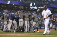 Colorado Rockies' Matt Holliday, front, walks off the field as members of the Milwaukee Brewers celebrate after the ninth inning of Game 3 of a baseball National League Division Series Sunday, Oct. 7, 2018, in Denver. The Brewers won 6-0 to sweep the series in three games and move on to the National League Championship Series. (AP Photo/Joe Mahoney)