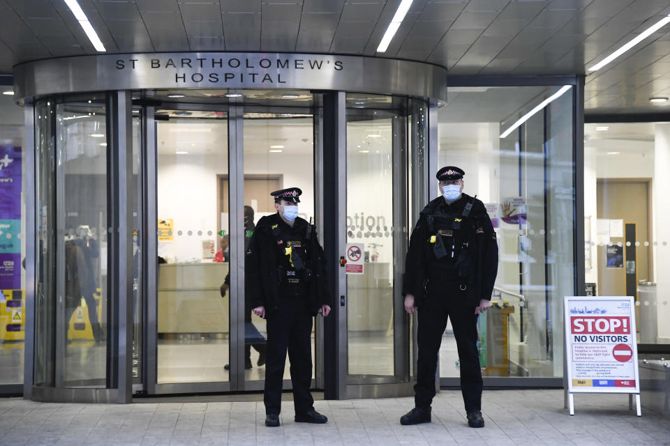 Police officers stand outside the main entrance of St Bartholomew's Hospital where Britain's Prince Philip is being treated, in London, Thursday, March 4, 2021. Buckingham Palace said Philip, the 99-year-old husband of Queen Elizabeth II, was transferred from King Edward VII's Hospital to St Bartholomew's Hospital on Monday to undergo testing and observation for a pre-existing heart condition as he continues treatment for an unspecified infection.(AP Photo/Alberto Pezzali)