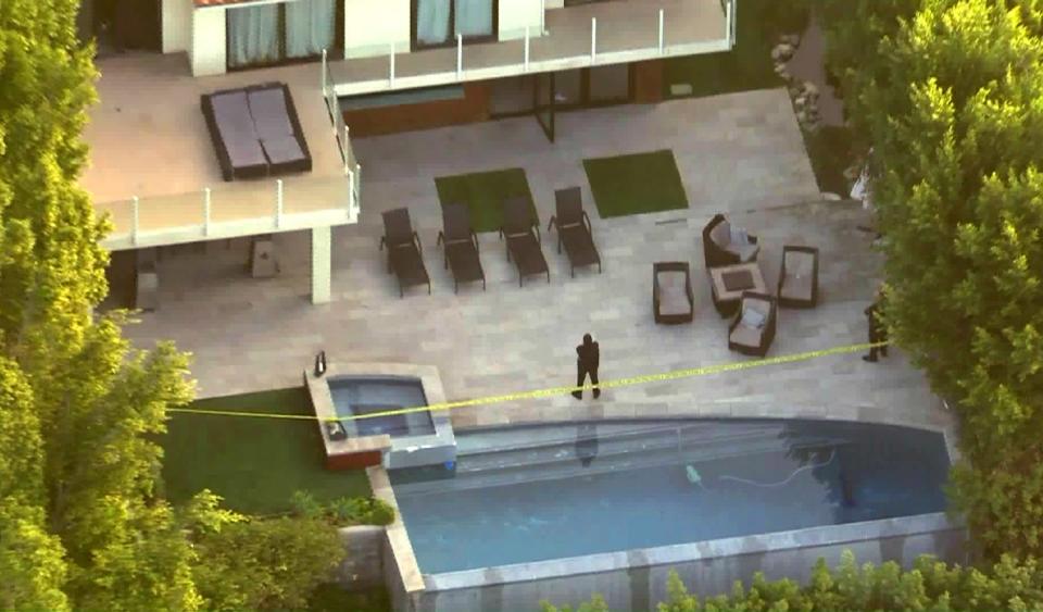 An aerial view shows a pool and patio behind a home