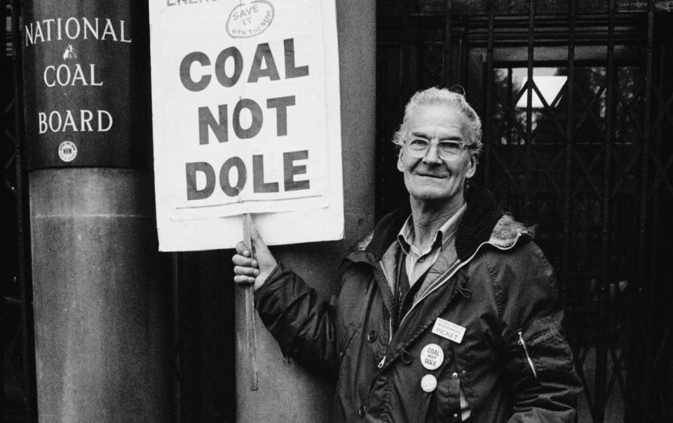 A protester holding a 'Coal Not Dole' placard outside the headquarters of the National Coal Board at Hobart House in Grosvenor Place in  1984