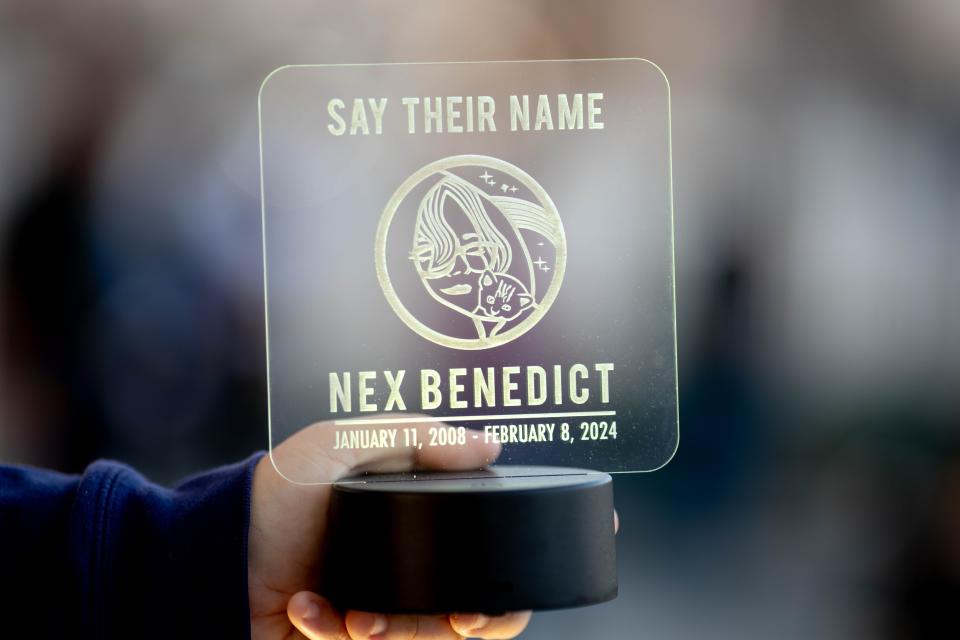 Micah Hillenberg holds an etched piece of plastic during a vigil for for Nex Benedict on Feb. 25 at Redbud Festival Park.