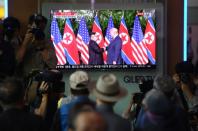 Commuters in Seoul gather around a screen at a railway station to watch live footage of the historic handshake