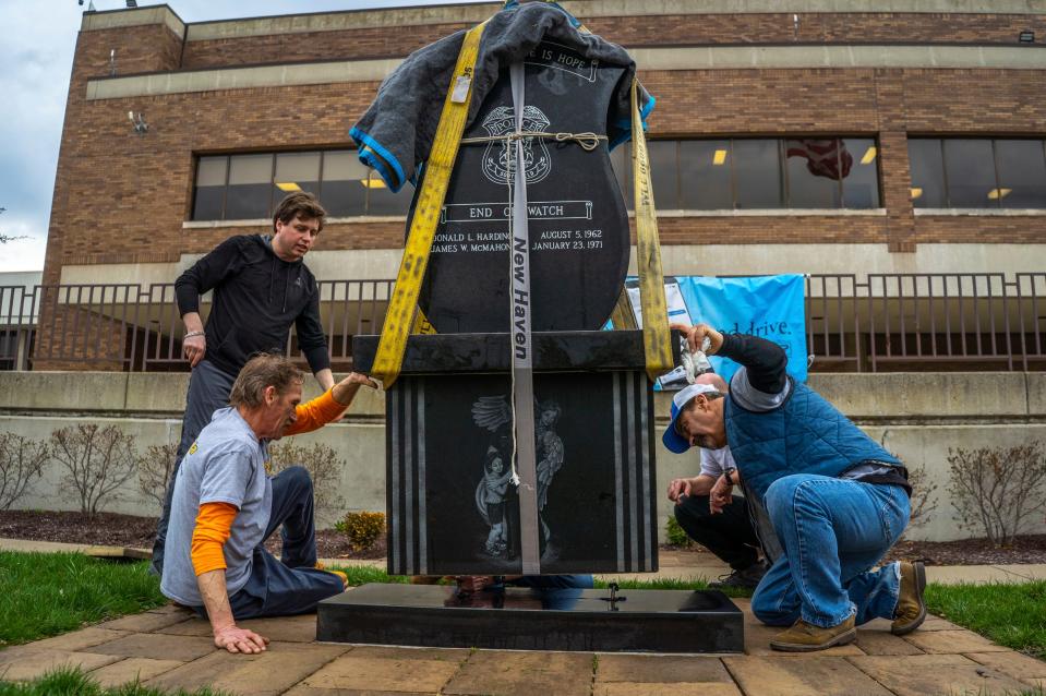 (Left to right) J. Noseda &amp; Son Inc. co-owner Jake Noseda watches as Ken Noseda and Steven St. John help guide Southfield Police Department's &quot;Fallen Hero&quot; granite sculpture as it is lined up while being lowered into position using a backhoe while moving it to a more visible spot outside of the Southfield Police Department building in Southfield on Wednesday, April 5, 2023.