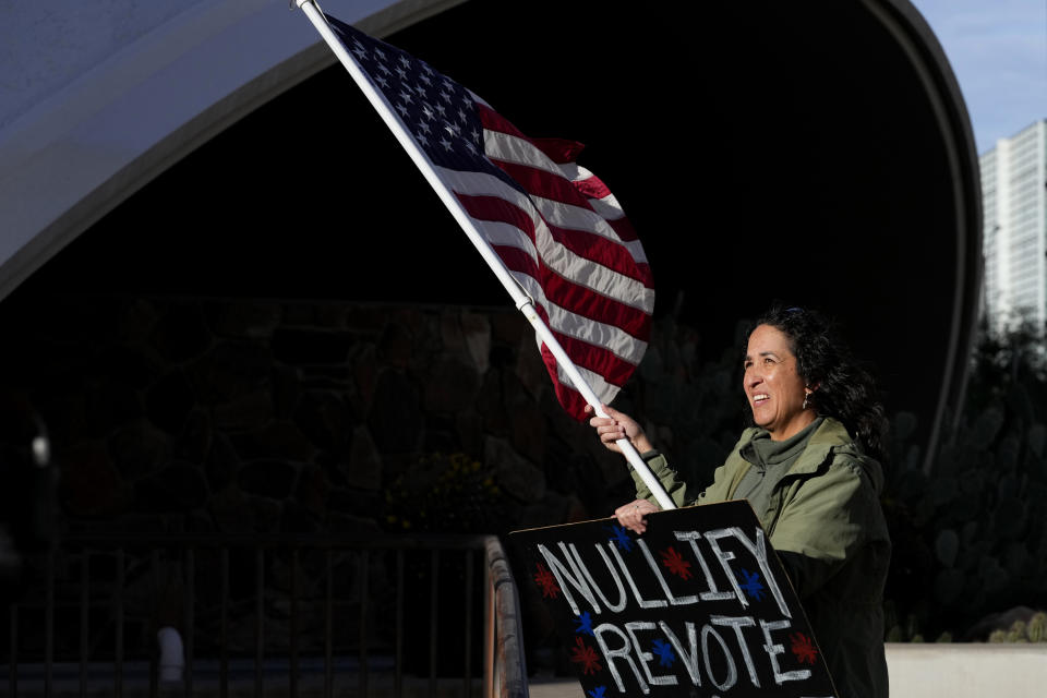 FILE - A woman stands in protest outside the Maricopa County Board of Supervisors auditorium prior to the board's general election canvass meeting, Nov. 28, 2022, in Phoenix. A ghost from recent election cycles, controversies over certification of results, is beginning to re-emerge as the nation heads closer to the 2024 presidential contest. (AP Photo/Matt York, File)