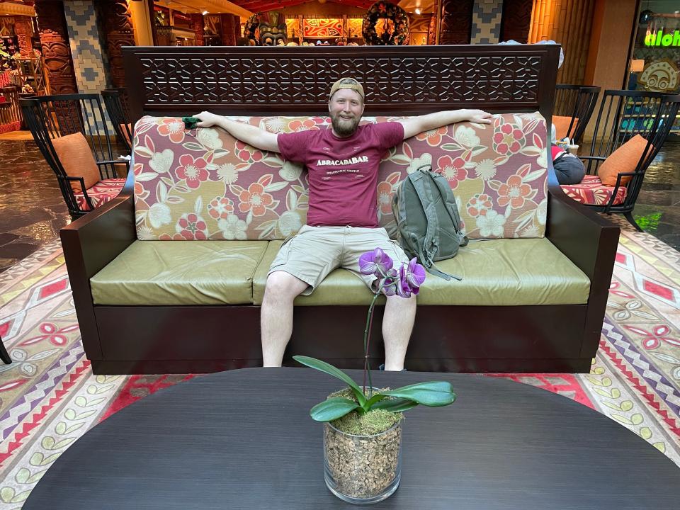 Author sits on cushioned bench on first floor of Polynesian Village Resort