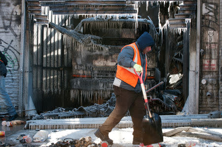 FILE PHOTO: A worker cleans up after a large fire extinguished by the New York Fire Department (NYFD) as they worked in frigid conditions in the Brooklyn Borough of New York, U.S., January 31, 2019. REUTERS/Lloyd Mitchell/File Photo