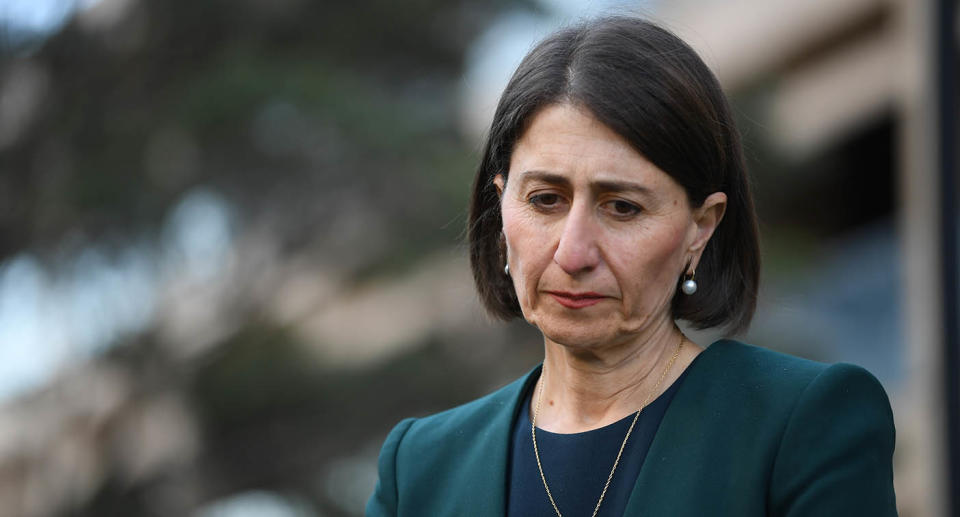 Gladys Berejiklian wearing green looking sad looking downwards.