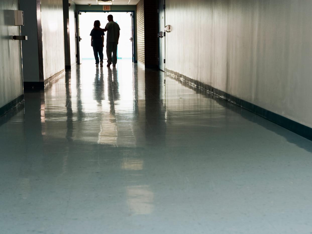 Two figures at the end of a long hospital corridor