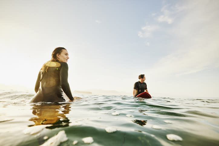 Woman and man on their surfboards in the middle of the ocean