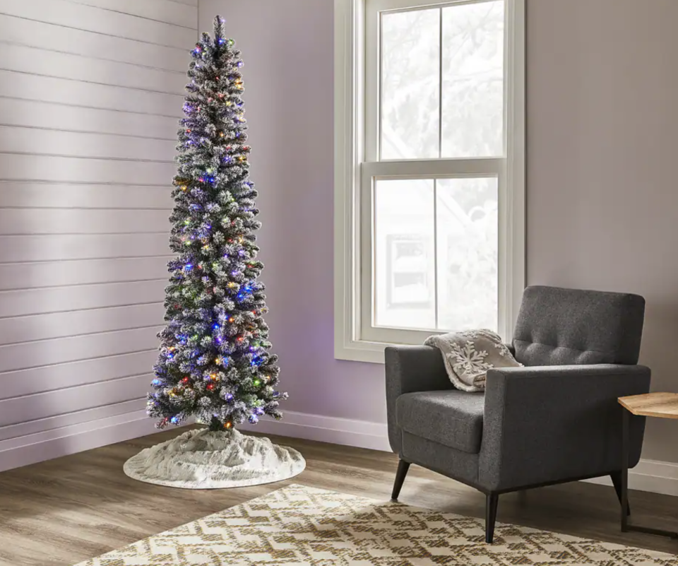 Noma Pre-Lit Bennet Pencil Christmas Tree in living room corner against white wall near chair (Photo via Canadian Tire)