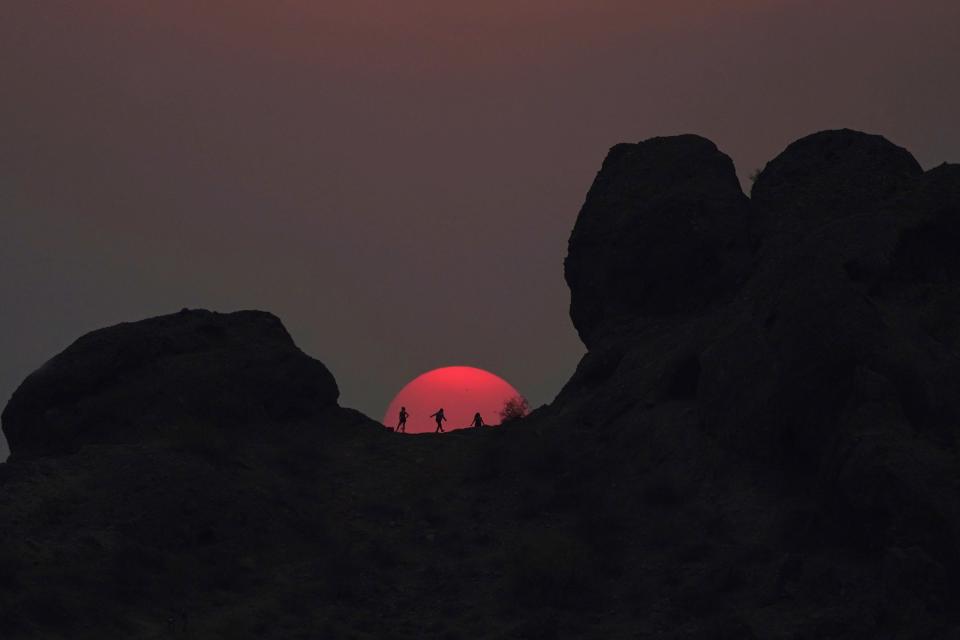 Hikers pause to watch the sunset at Papago Park during a heatwave where temperatures reached 115-degrees Tuesday, June 15, 2021, in Phoenix. (AP Photo/Ross D. Franklin)