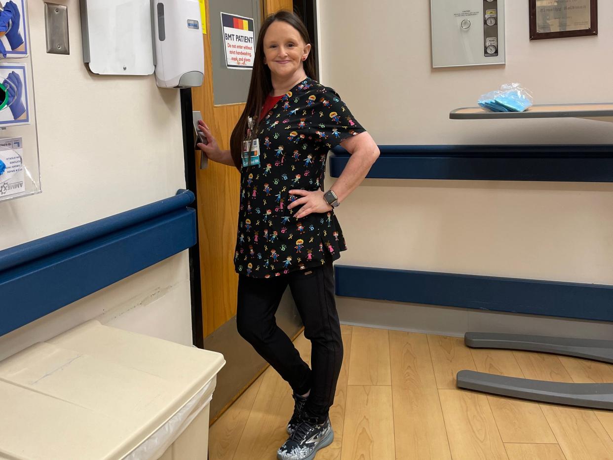 Laura Shinn working as a nurse posing by door wearing scrubs