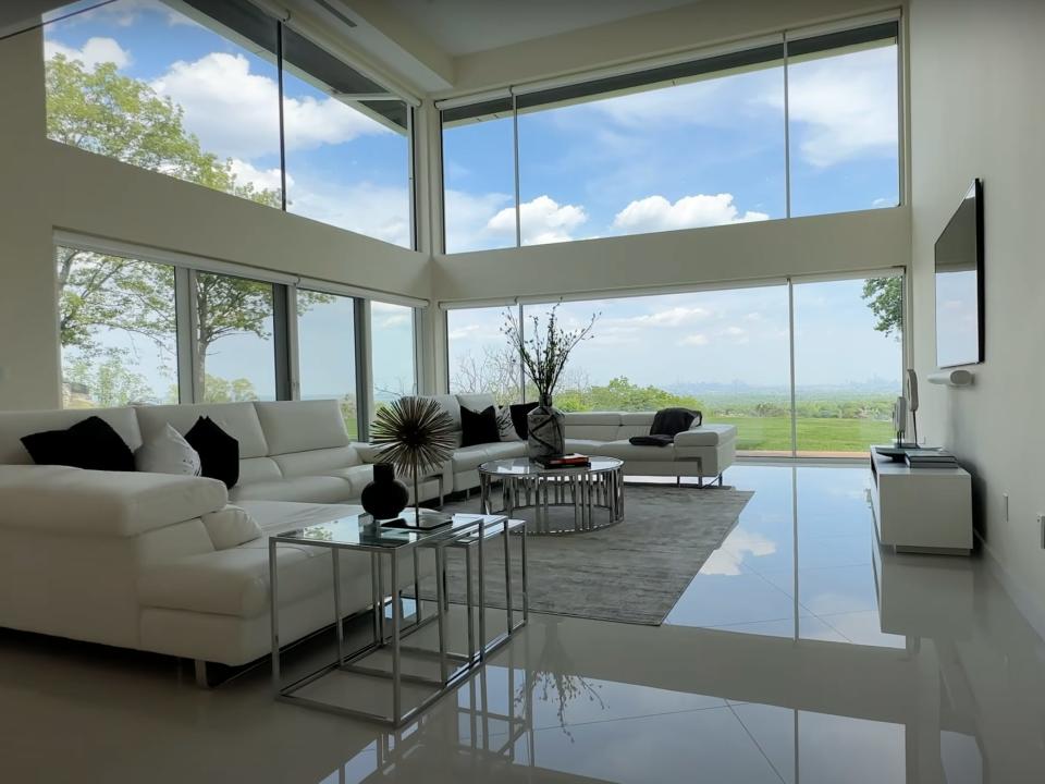 A white, modern living room with large windows.