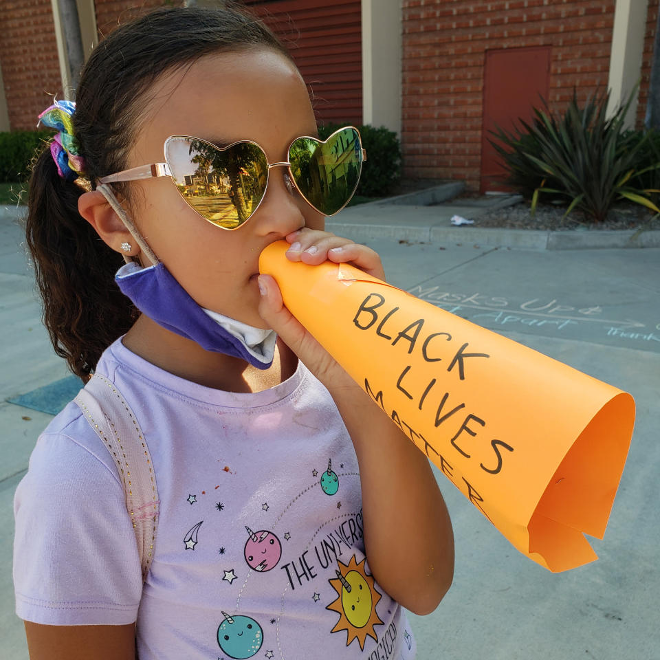 Bella De La Rosa, 9, holds a paper megaphone up to her mouth at a Black Lives Matter event in Los Angeles on Aug. 2, 2020. "I want to be louder," Bella told her mother before the racial justice protest. Their solution: a paper megaphone with the words “Black Lives Matter.” "I love to watch her chanting as loud as she can, using her voice," said her mother, Mary De La Rosa. "It's been a year of her learning to use her voice and to use it proudly." (Mary De La Rosa via AP)