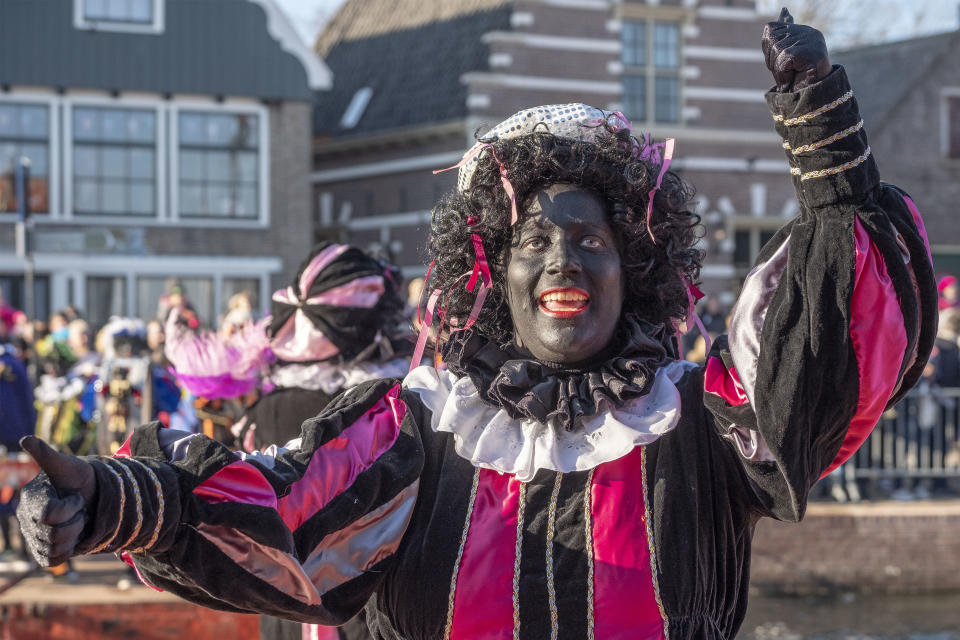 FILE - In this Saturday, Nov. 17, 2018, file photo, a Black Pete interacts with children during the arrival of Sinterklaas in Monnickendam, Netherlands. Facebook announced Tuesday, Aug. 11, 2020, that it is banning caricatures of Black people in the form of blackface, as well as dehumanizing depictions of Jewish people that include images or posts of Jewish people running the world or controlling major institutions such as media networks, the economy or the government. Zwarte Piet is a sidekick of Sinterklaas, the Dutch version of St. Nicholas a Santa-like character who brings children gifts. (AP Photo/Patrick Post, File)