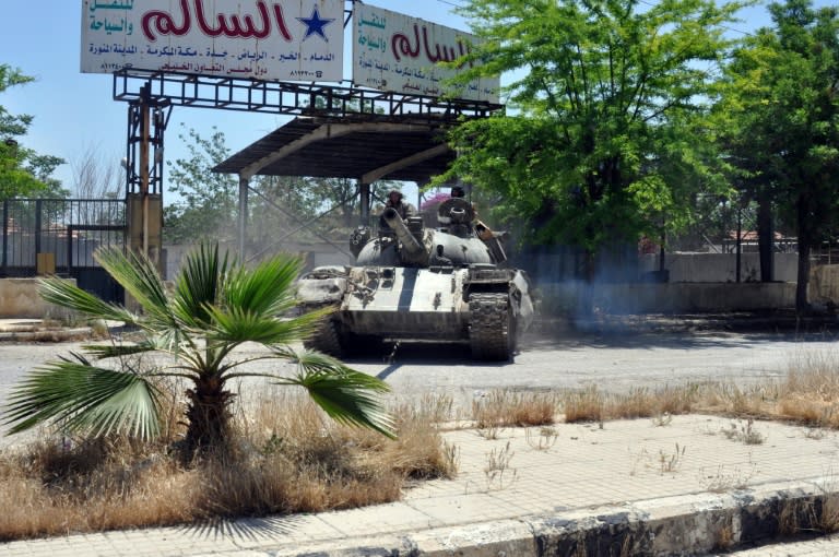 A Syrian government tank drives down a street in Al Hajar al Aswad, during a regime offensive targeting the Islamic State group in the southern districts of Damascus