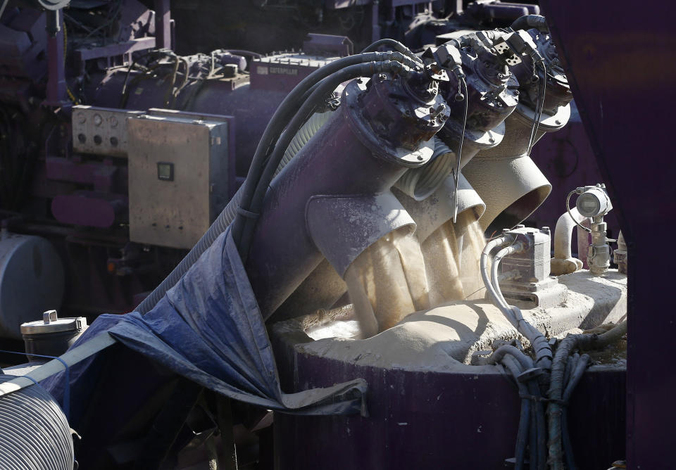 In this March 25, 2014 photo, a machine mixes sand and water, left, before it is pumped underground during a hydraulic fracturing operation at an Encana Corp. well pad near Mead, Colo. Hydraulic fracturing, or "fracking,"is the practice of injecting water, sand and chemicals into source rock to crack it and create escape routes for oil and gas. (AP Photo/Brennan Linsley)