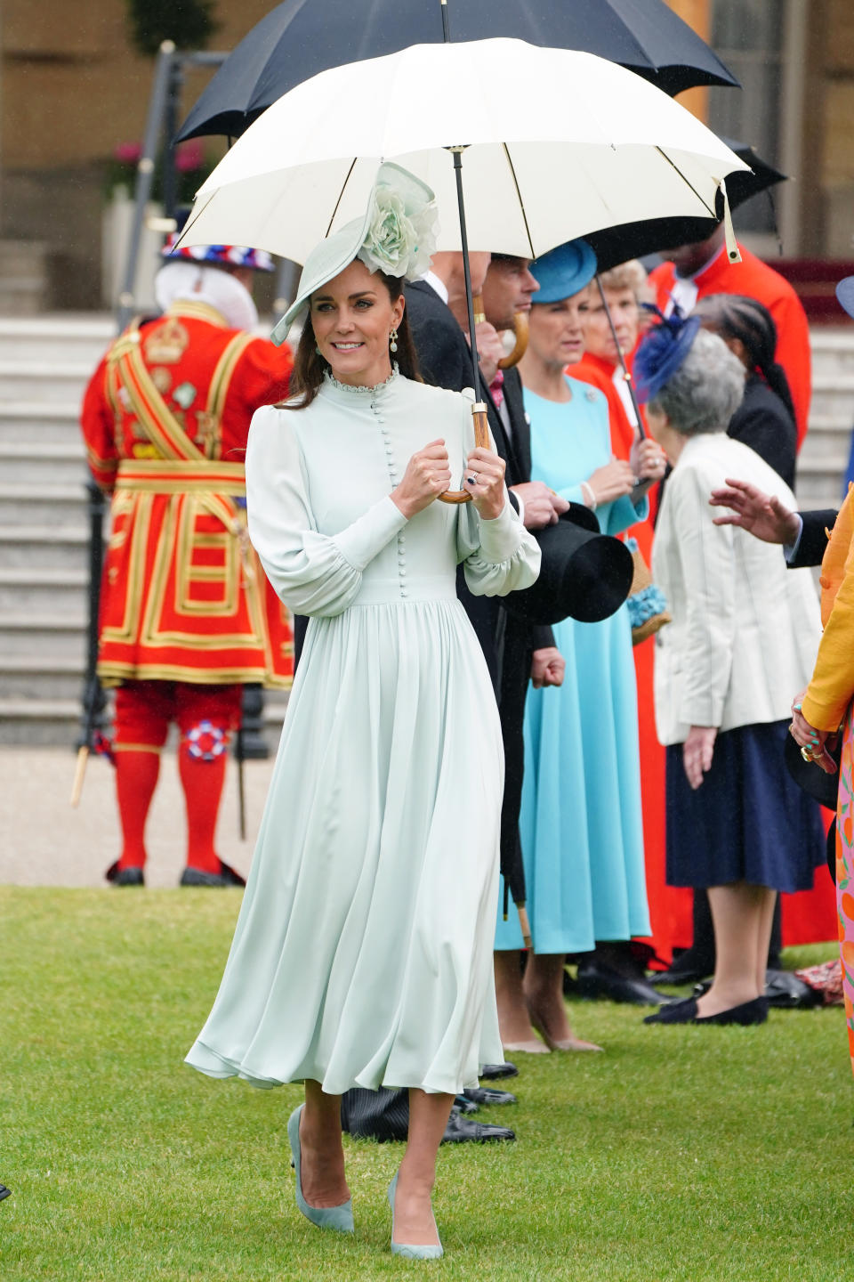 Catherine, Duchess of Cambridge crosses the lawn at the garden party wearing her mint dress with a matching parasol.