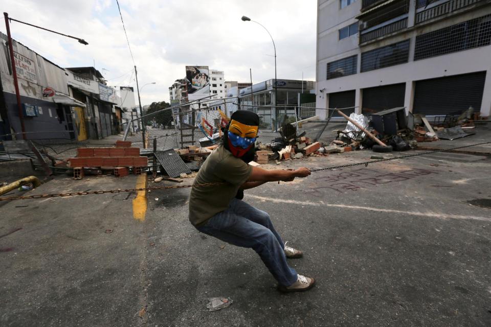 Un manfestante enmascarado hala una cadena para evitar que la Guardia Nacional se acerque durante enfrenamientos en Caracas, Venezuela, el domingo 2 de marzo de 2014. (Foto AP/Fernando Llano)