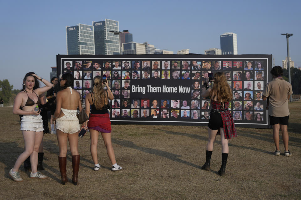 Personas toman una pausa frente a fotogrfías de rehenes cautivos en Gaza en el concierto Nova Healing en Tel Aviv, Israel, el jueves 27 de junio de 2024.Esta fue la primera reunión masiva de Tribe of Nova desde el ataque de Hamas del 7 de octubre de 2023 que dejó a cientos de heridos y secuestrados en el festival de música Nova. (Foto AP/Ohad Zwigenberg)